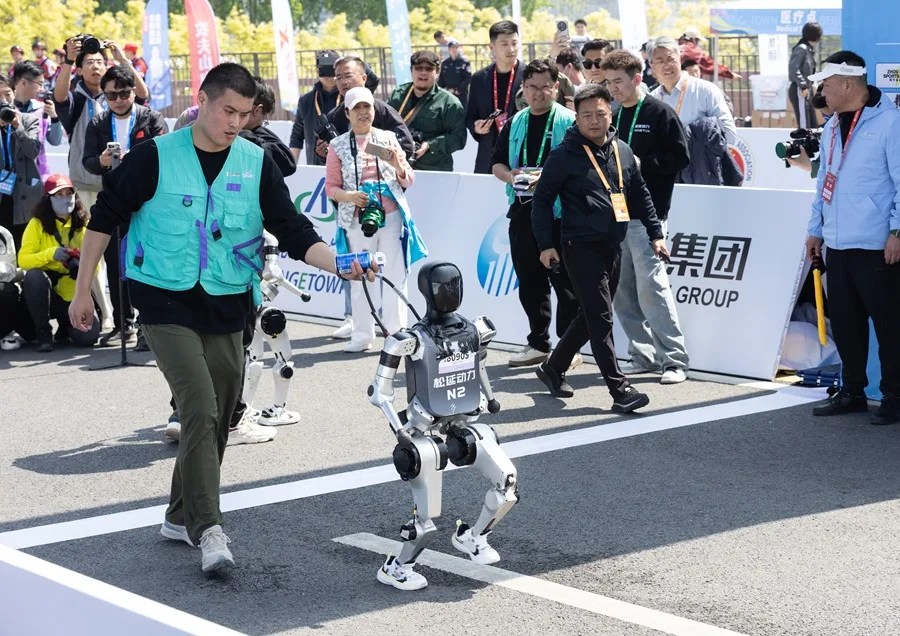 Un robot celebra tras cruzar la meta durante un maratón en Pekín